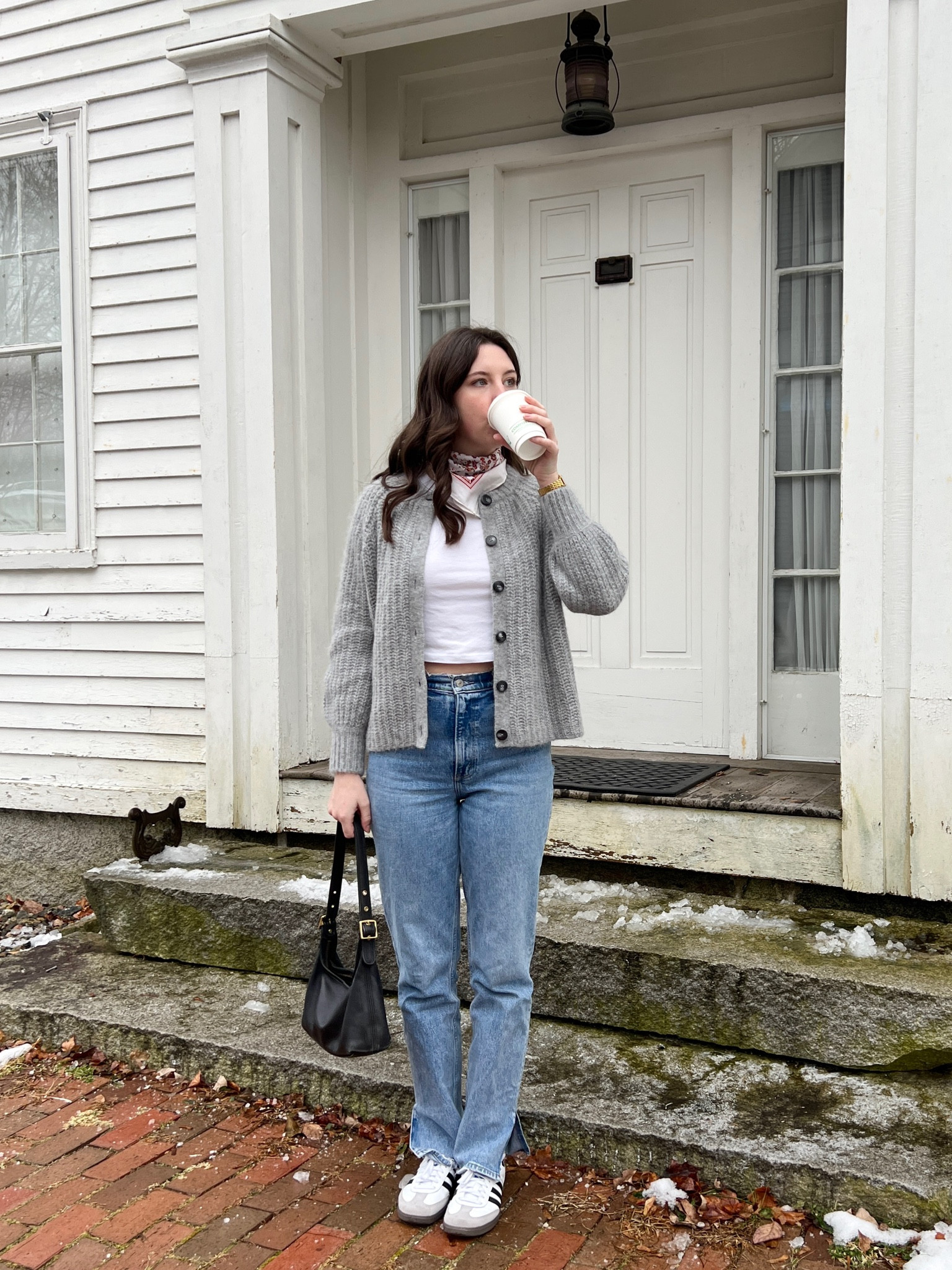 Winter cozy outfit with jeans, grey chunky knit cardigan, white t shirt, black shoulder bag, and adidas sambas 
