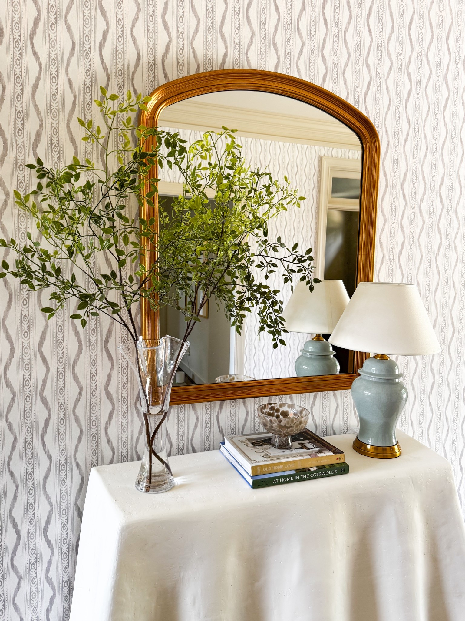 Entryway decor! Ikat taupe wallpaper, arched gold mirror, oversized faux branches, traditional  lamp from Amazon, and wavy console (unfortunately discontinued) but linking for you to see dimensions! 

#LTKStyleTip #LTKFindsUnder100 #LTKHome