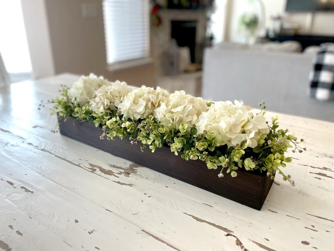 Bring a warm, custom touch to your space with this handcrafted farmhouse centerpiece, designed to fit beautifully on a dining table, mantle, or kitchen island. Made from premium pine wood and finished to match your style, each piece can be personalized with your choice of florals—from soft antique whites to lush greenery—creating a look that feels uniquely yours. With multiple sizes available, it’s an easy way to elevate everyday decor or make a statement for gatherings. #LTKhome #farmhousedecor #customhome #rusticstyle #tabledecor #homestyling #cozyspaces #decorinspo

#LTKSeasonal #LTKHome #LTKWedding