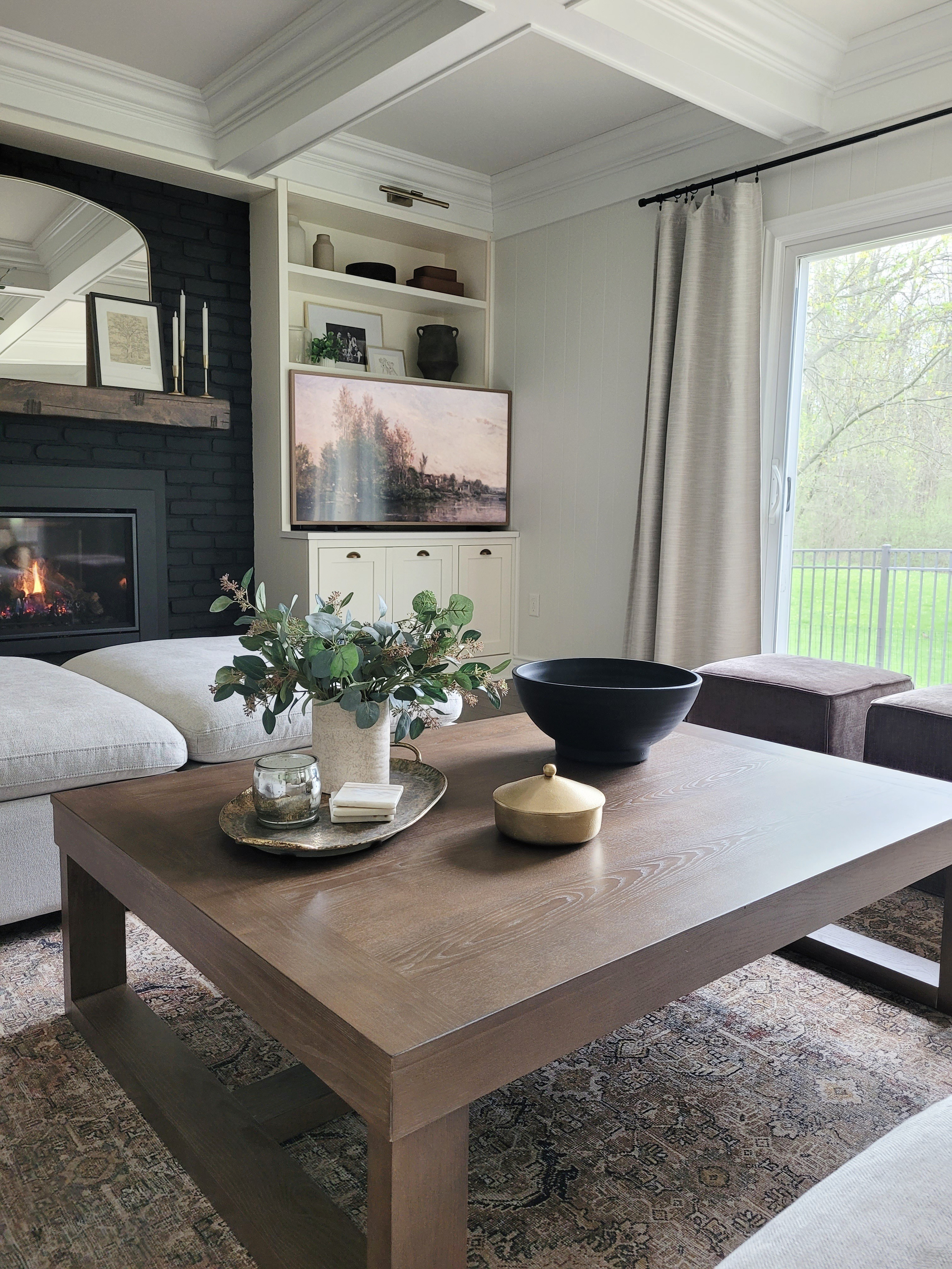 One of my favorite inexpensive home updates - painting our fireplace black! Cozy family room with a vintage inspired rug, affordable coffee table,  and sectional sofa. Living room,  fall home. Fall decor,  mantle decor 

#LTKHome