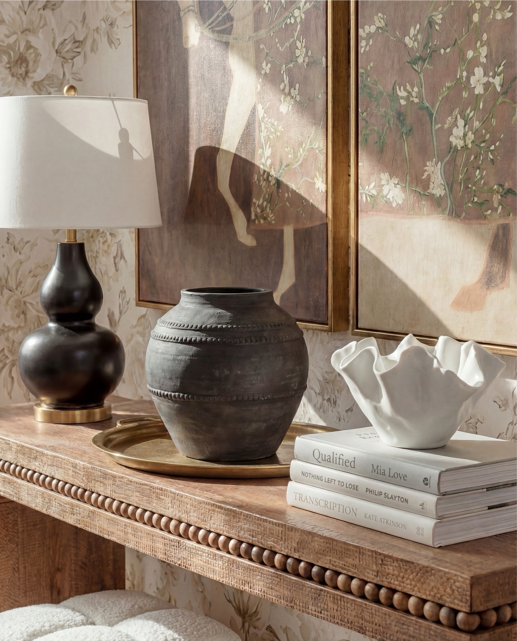 Shop the Look:
• Neutral floral wallpaper (beige + taupe tones)
• Solid wood console table (warm oak finish)
• Beaded edge console table detail
• Framed vintage-style art prints (earthy brown tones)
• Brass picture frames
• Black ceramic table lamp with white shade
• Decorative table tray (antique brass)
• Stone or ceramic vase (charcoal gray)
• Sculptural white bowl (organic shape)
• Coffee table books (neutral covers)
• Bouclé cube ottomans (ivory)
• Light wood flooring
• Vintage-style area rug (muted beige + gray)
• White baseboards and trim

#LTKHome #LTKSaleAlert