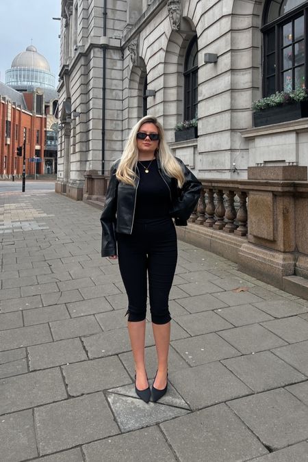 an all black outfit with a cropped leather collar jacket, black prada sunglasses, a gold locket necklace, black slash neck fitted top, black capri pants/pedal pushers, black pointed kitten heels and a black coach the hamptons shoulder bag as a spring 2024 outfit 

#LTKstyletip #LTKeurope #LTKSeasonal