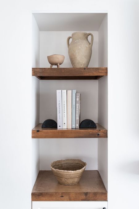 Rustic living room shelves decorated with books, vases, and bowls. Not pictured, black wall sconce centered over shelves. 

Wooden shelves, home decor, interior design books, vases, bowls, book ends, shelf styling, living room. 


#LTKunder50 #LTKunder100 #LTKhome