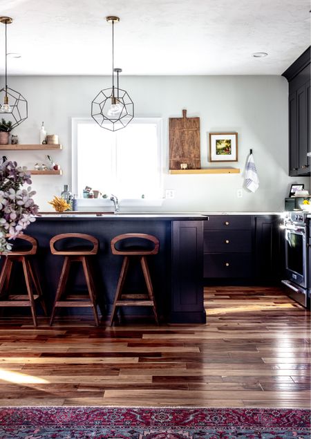 Black kitchen with mid century modern walnut counter stools, brass knobs, modern brass pendants, floating shelves, and vintage bread board

#LTKhome #LTKFind