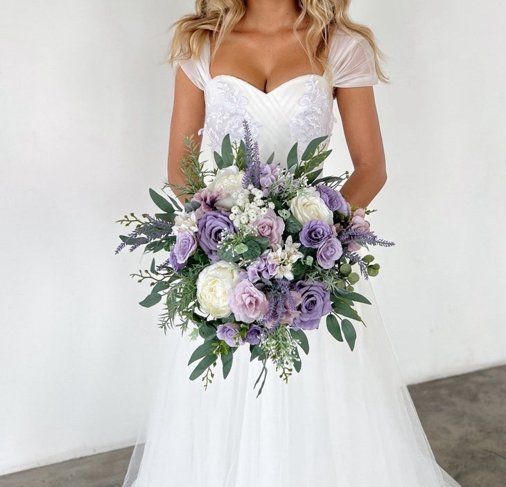 This lavender and lilac bridal bouquet is a beautiful choice for a romantic, garden-inspired wedding. Soft shades of purple, white, champagne, and eucalyptus greenery create a delicate and dreamy palette that feels both fresh and timeless. Finished with a champagne satin ribbon-wrapped handle, this silk flower bouquet offers effortless elegance while staying picture-perfect from ceremony to celebration—and for years to come. #LTKwedding #lavenderwedding #bridalbouquet #purplewedding #weddingflowers #bridestyle #gardenwedding #silkflowers #weddinginspiration #bridetobe

#LTKWedding #LTKHome #LTKSeasonal