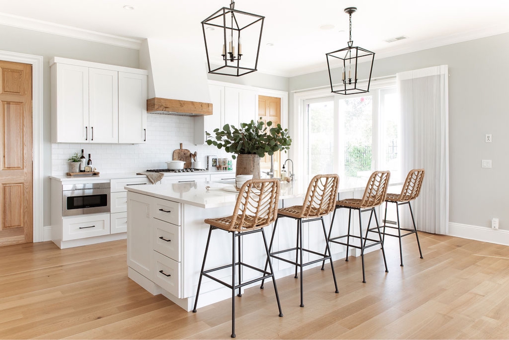 Encinitas Ranch kitchen remodel- white oak flooring, white shaker cabinetry, quartz countertops, black pendant lighting, wicker counter stools, and subway tile backsplash. #LTKHoliday 

#LTKhome #LTKstyletip