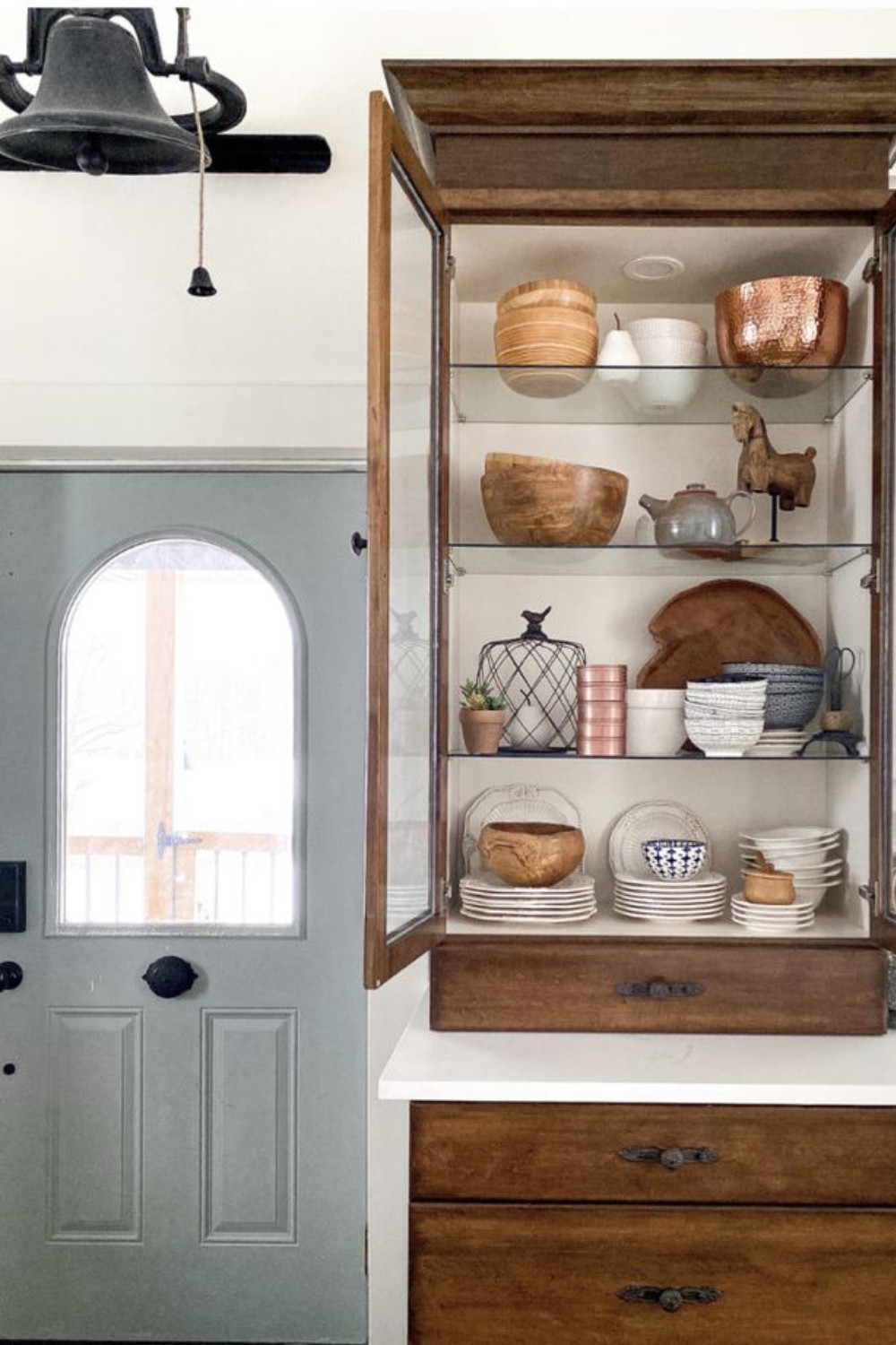 Bring character to your kitchen with this bold and earthy-inspired design! This design features rustic elements with a cast iron bell, wood bowls, and vintage dinnerware. A pop of color with Magnolia's "Sir Drake" paint and all balanced out by Magnolia's "Cupola" white. 

 #LTKSeasonal #LTKHome #LTKStyleTip