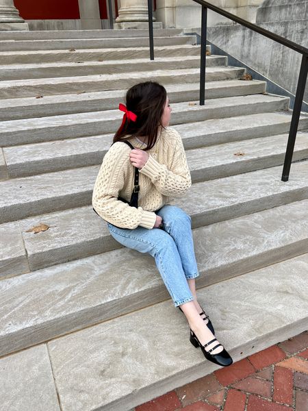 Winter city style outfit with black flats, light wash denim jeans, chunky knit cream fisherman’s sweater, and red hair bow 

#LTKSeasonal