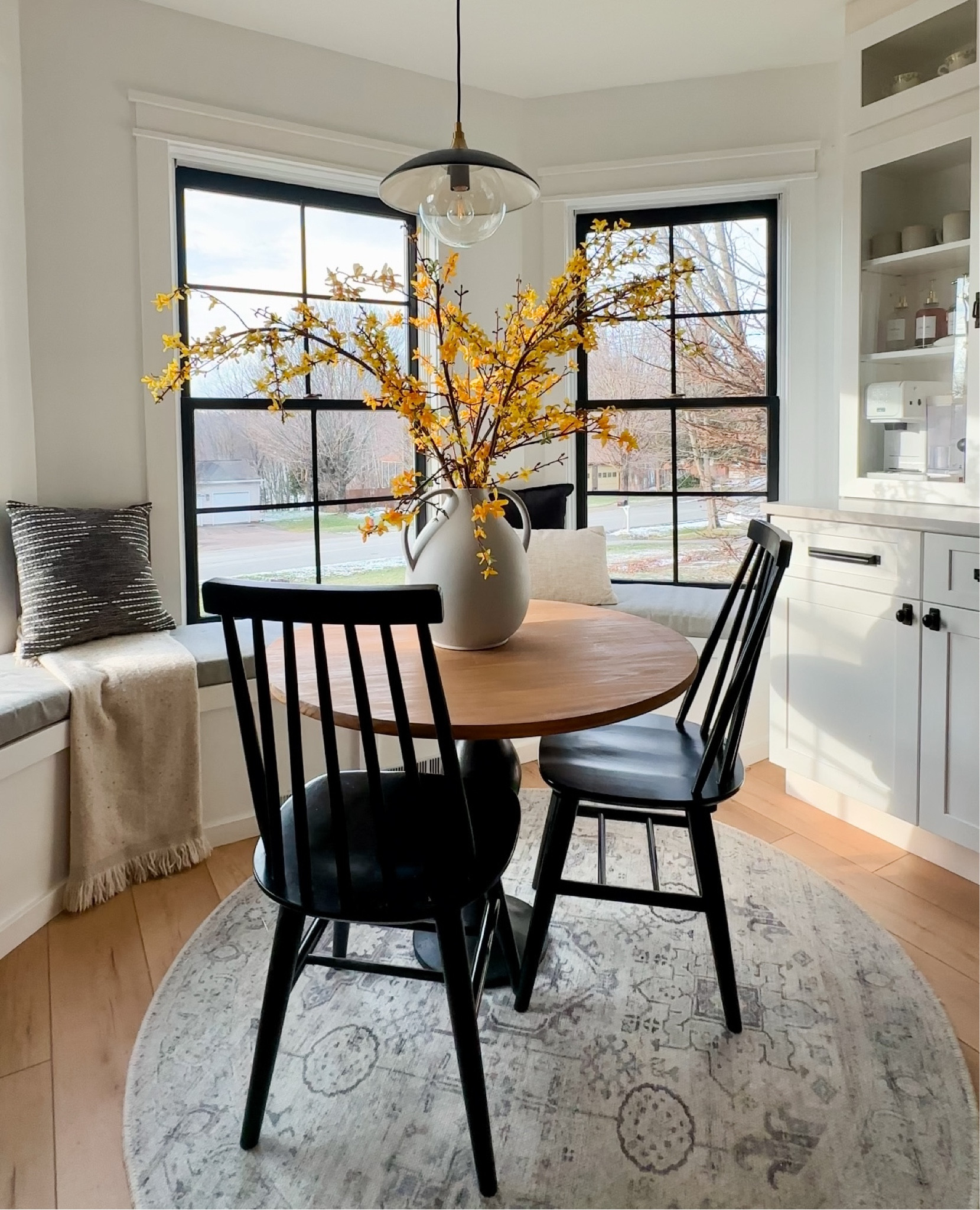 View of my kitchen nook and coffee bar. 

🏷️ breakfast bar , breakfast nook , coffee bar , window seat , kitchen pendant , mid century pendant , black chairs , round rug , faux flowers , floral stems , spring kitchen styling

#LTKSeasonal #LTKHome #LTKStyleTip