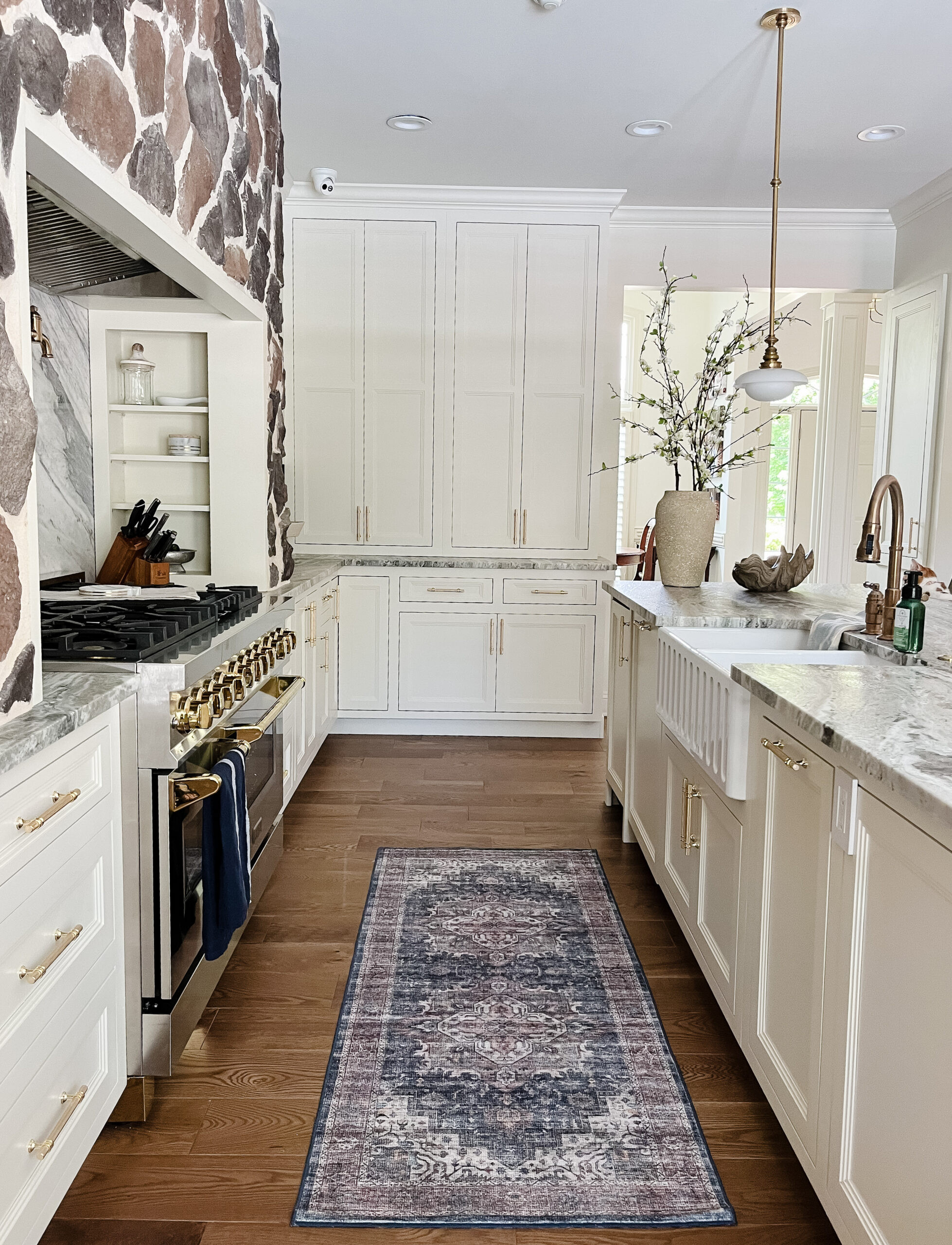 Open sightlines, layered texture, and timeless finishes ✨ Removing the wall completely transformed the energy of this home, and that stone range hood steals the show. Soft-veined quartz with a full-height slab backsplash keeps everything feeling seamless, while ceiling-height cabinetry, classic pendants, and upgraded appliances bring a modern polish that still feels warm and livable. Shop a similar look for your own kitchen refresh below. 🤍 

 #LTKHome