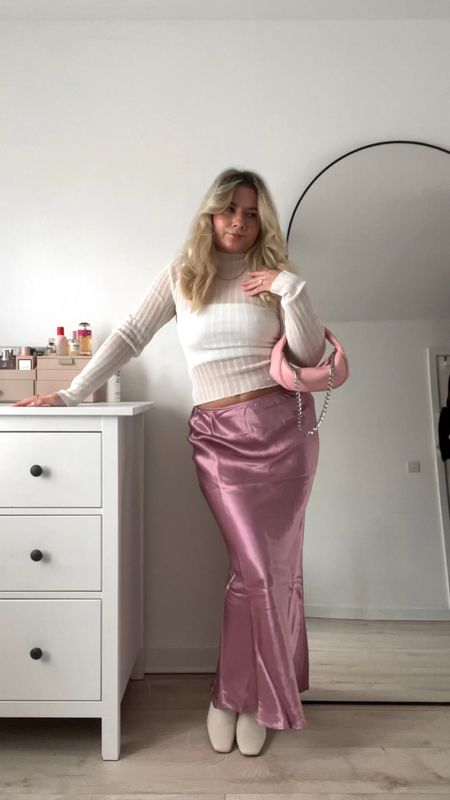pink maxi satin skirt, white bandeau top, white sheer ribbed long sleeve top, pink by far baby cush shoulder bag, white/cream knee high boots and a cream oversized coat

#LTKstyletip #LTKeurope #LTKitbag