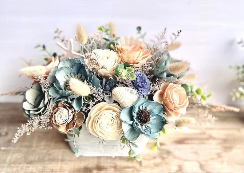 Add a splash of seaside charm to your space with this coastal floral arrangement by ForeverFlowersbyGigi. Styled in a whitewashed galvanized tin, it features soft ocean blues, breezy greens, and sandy blush tones paired with natural bark sola wood blooms and scattered seashell accents for the sweetest beachy touch. Perfect for a dining table, entry console, or summer mantel, this piece brings relaxed coastal vibes without any maintenance. Available in multiple sizes and customizable colors to fit your décor, plus coordinating bridal bouquets and wall décor in the same design.

#LTKHome #CoastalStyle #BeachDecor #SolaWoodFlowers #SummerDecor #NauticalHome #EtsyHome #CoastalLiving

#LTKSeasonal #LTKHome #LTKWedding