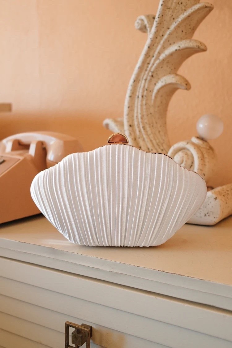 The Divan White Pleated Satin Seashell Clutch brings an elegant coastal touch to evening dressing with its sculptural seashell-inspired silhouette and luminous satin finish. A beautiful finishing touch for weddings, resort dinners, summer celebrations, and special occasions. Under $40.

Ideas:

* white clutch
* seashell clutch
* wedding guest accessories
* summer evening style
* resort fashion

#LTKgrwm #LTKTravel #LTKWedding