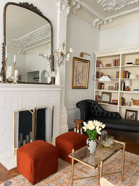 Living room, Decour and furniture. Area, rug, floor lamp, picture, light, mirror, fireplace screen, velvet Ottomans, rectangular, glass, coffee table, gold wall sconces.

#LTKFind #LTKhome #LTKstyletip
