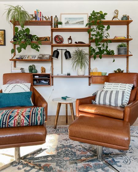 How to create a cozy MCM living room.  Wall mounted shelves, leather swivel chairs, lots of plants and of course a brass animal!

#LTKhome