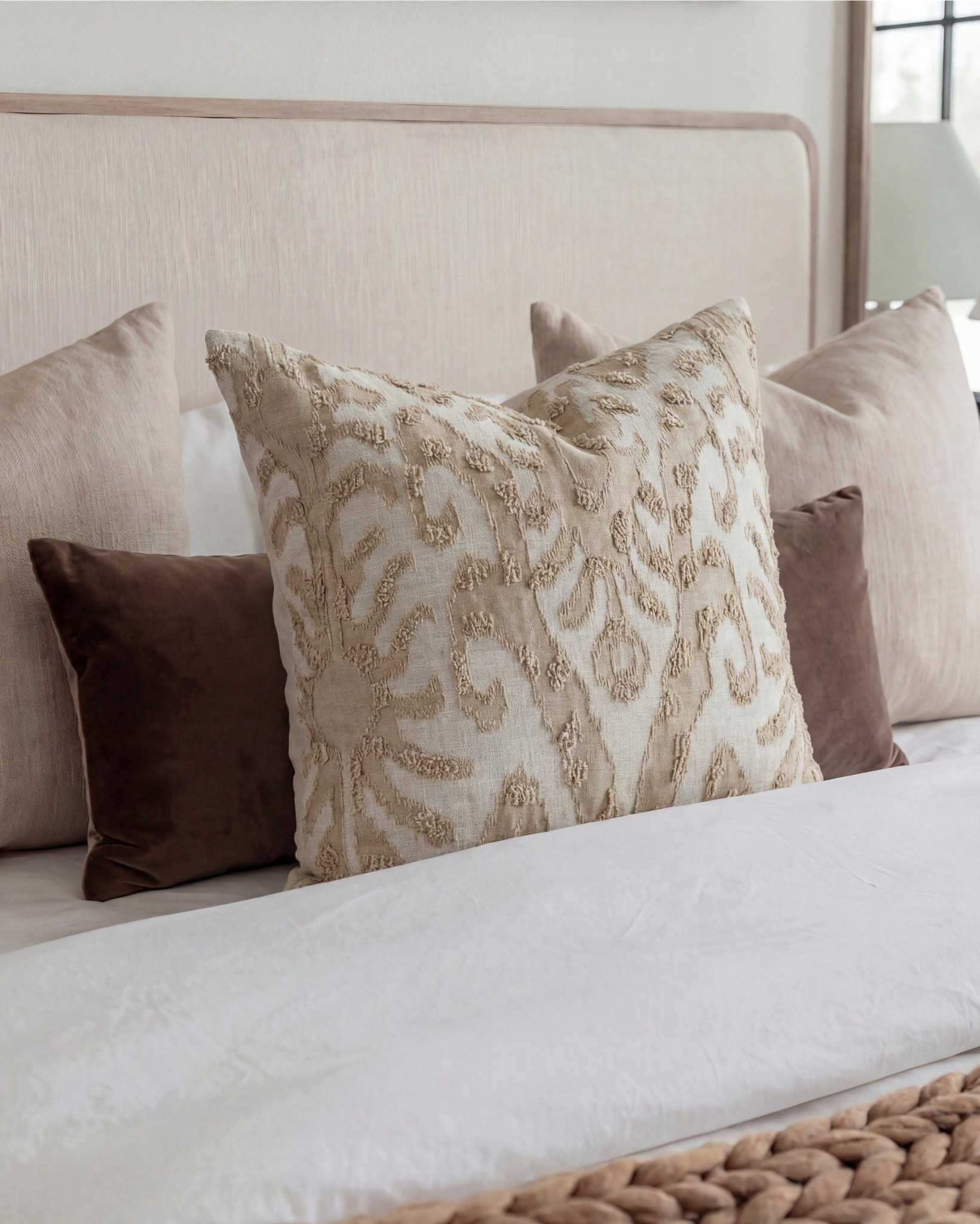 Shop the Look: Bedroom Refresh
• Upholstered bed frame (light neutral fabric)
• White cotton duvet cover + pillow shams
• Neutral patterned area rug
• Chunky knit throw blanket (warm beige)
• Woven knit poufs (foot-of-bed seating)
• Dark wood nightstands with brass pulls
• Sculptural white ceramic table lamps
• White tapered lamp shades
• Brass-framed rectangular mirrors
• Framed floral artwork (warm, moody tones)
• Neutral linen accent pillows
• Ceramic decorative bowl (white sculptural style)
• Small glass vase with white florals

#LTKhome #LTKsale #LTKstyletip