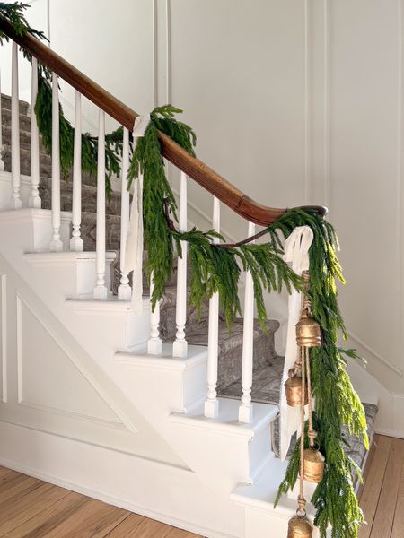 Staircase decorated with pine garland, white velvet ribbon and brass Christmas bells. 

#LTKSeasonal #LTKHoliday #LTKhome