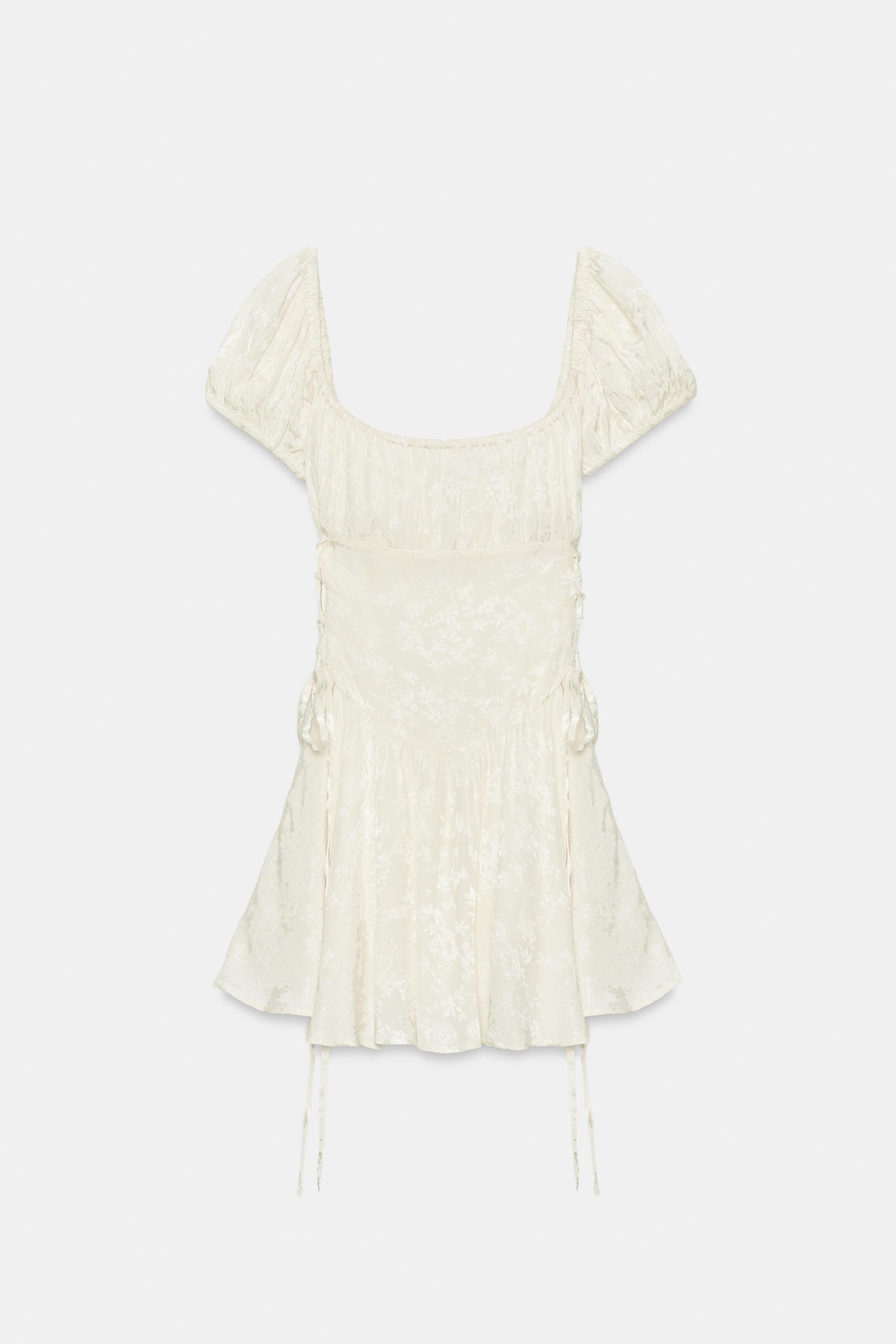 Round neck dress with elasticated short sleeves. Jacquard fabric detail and crisscross ties at th... | Zara US