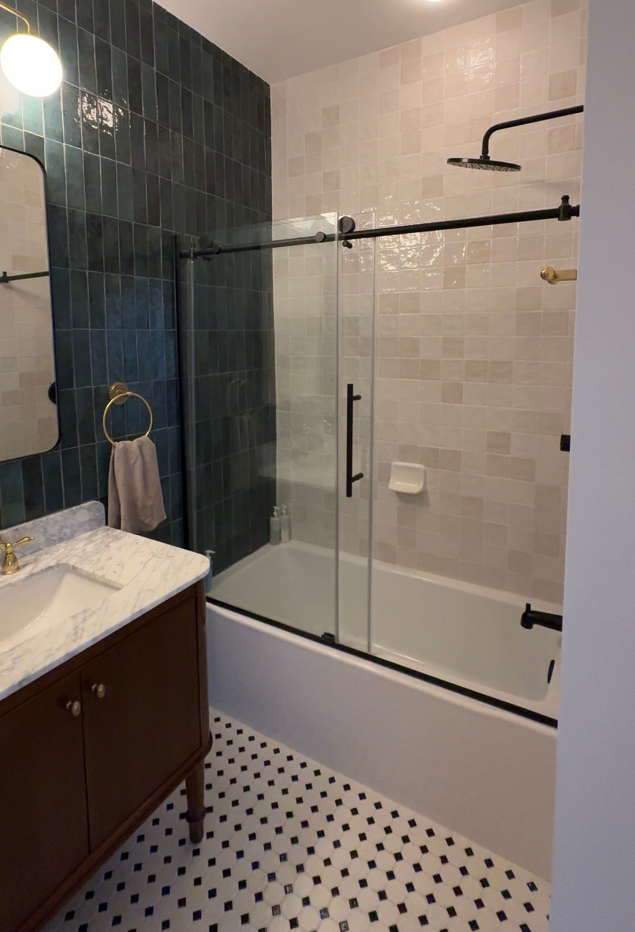The guest bathroom transformation is everything I hoped it would be! The standout feature is the green rectangular tile that covers the entire back wall—it instantly makes the room feel fresh and unique. I paired a marble-top brown vanity (from The Home Depot) with a vintage-inspired brass faucet, then layered in matching Claudette brass hardware: towel bar, towel ring, and toilet paper holder. Above the vanity, I added a chic round three-light fixture, and for the shower, we chose a clear tub door with black hardware for contrast. Every detail came together so beautifully!

#LTKFindsUnder100 #LTKHome