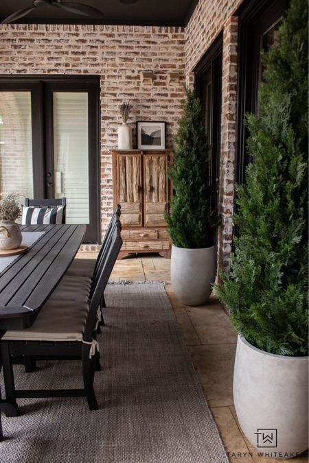 Outdoor dining area with black outdoor dining table and large concrete planters 

#LTKHome #LTKSeasonal