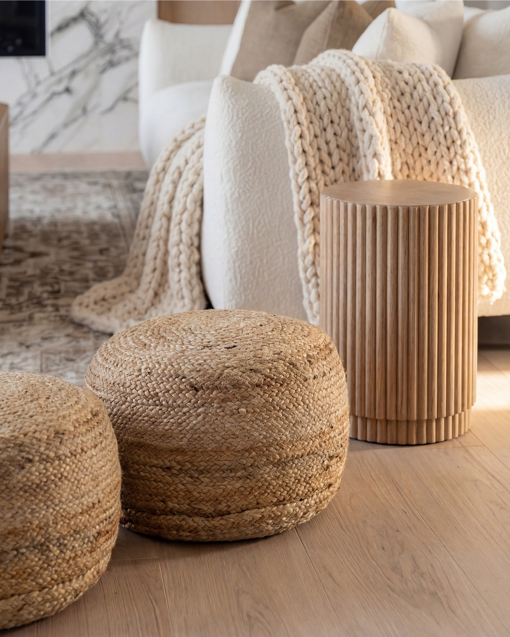 Soft, sculptural, and effortlessly serene — this living room blends creamy textures, warm woods, and a marble statement fireplace to create a calming, elevated retreat. The veined stone surround becomes the focal point, while the fluted coffee table and side tables bring subtle architectural interest. Layered neutrals in the sofa, knit throw, and accent pillows soften the space, and natural woven elements add warmth without overwhelming the palette. This is modern minimalism with soul — light, welcoming, and thoughtfully composed.

Shop the Look:
• Fluted light-oak coffee table
• Cream textured curved sofa
• Chunky knit throw in warm beige
• Neutral linen accent pillows
• Light-wood armchairs with cream cushions
• Marble fireplace surround panel
• Round glass pendant light
• Woven natural pouf stools
• Fluted wood side tables
• Vintage-inspired neutral area rug
• Potted faux olive tree

#LTKsale #LTKhome #LTKstyletip