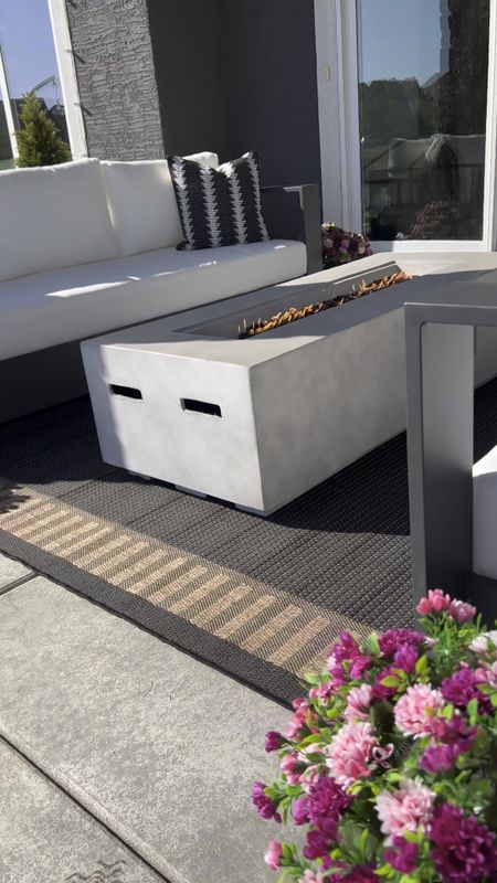 A rectangular concrete fire pit / fireplace makes any outdoor space extra cozy. I paired mine alongside two outdoor patio sofas. Click the links below to shop this exact look. 💕

Fire pit color - natural concrete
Outdoor rug - 7 feet 10 by 10feet
Faux Florals