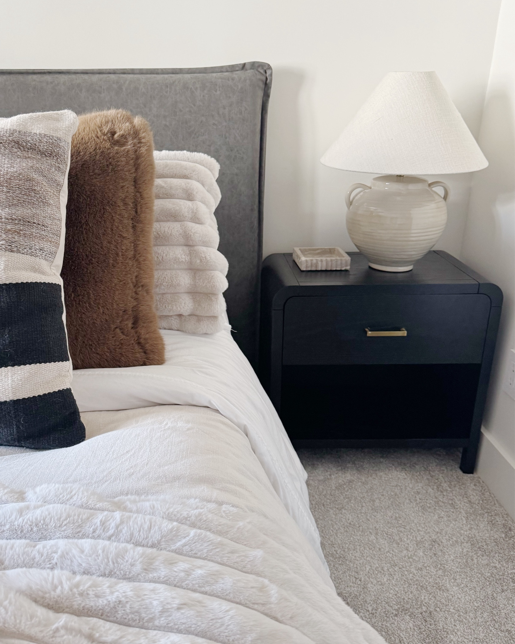 Neutral bedroom dreams! Cozy textures, moody tones, and the perfect blend of modern + organic details. I’m obsessed with this color palette and the soft layers on the bed — from faux fur to faux leather, it’s all about that elevated comfort. Linked my favorite Pottery Barn throw pillows, accent pieces, and bedding staples to help you recreate the look. #neutralbedroom #ltkhome #bedroomaesthetic #nightstandstyling#LTKStyleTip 

#LTKFindsUnder100 #LTKHome