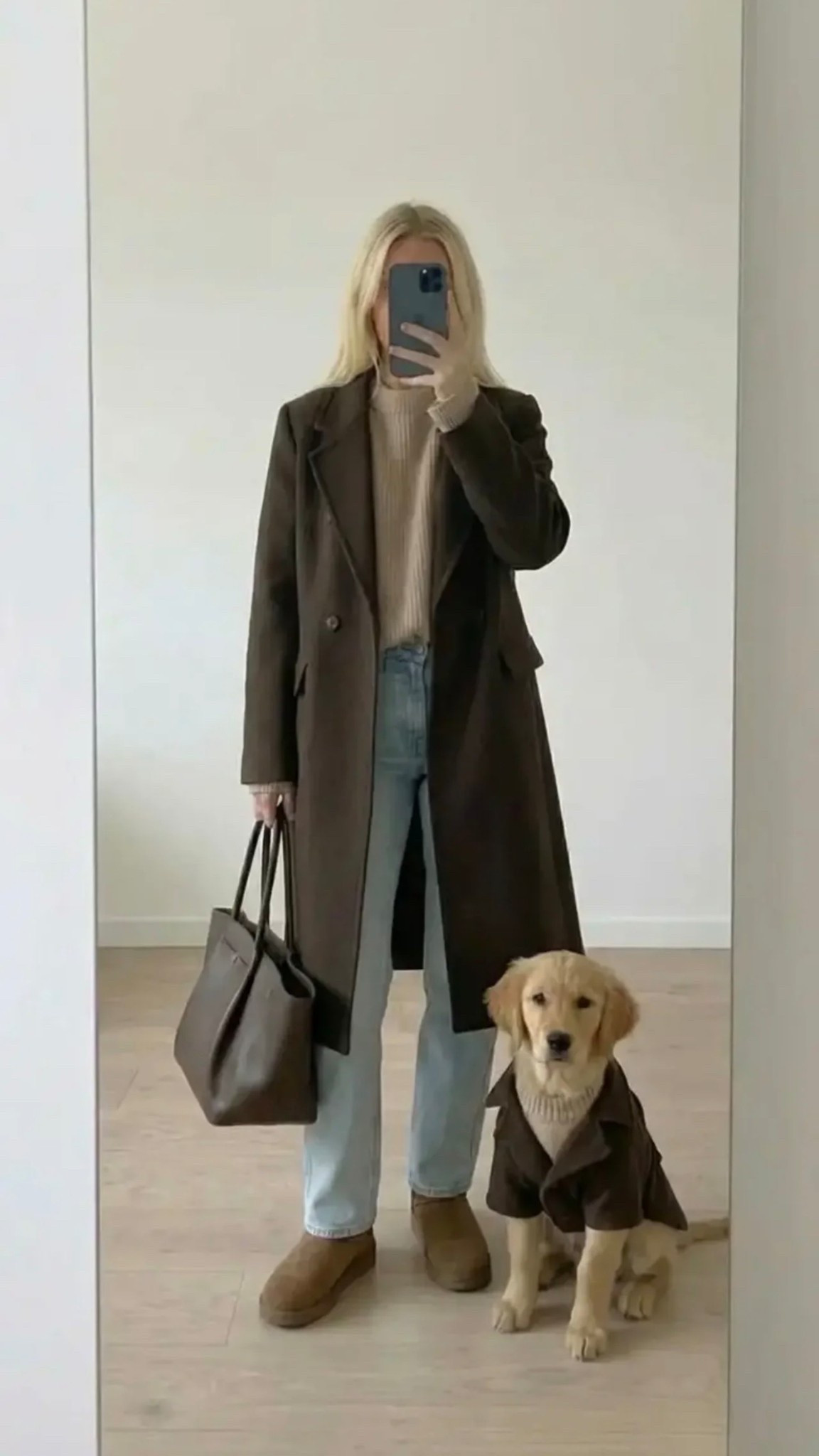 Minimalist mirror selfie of a chic woman in a neutral capsule wardrobe outfit: long dark brown tailored coat, beige ribbed turtleneck sweater, light-wash straight jeans, brown suede loafers, structured leather tote. Golden retriever puppy wearing matching coat and knit sweater beside her. Clean Scandinavian apartment, soft natural light, calm aesthetic, quiet luxury vibe, neutral palette, modern lifestyle fashion photography, vertical composition.

30 words (with /):
Tailored/long/brown/coat / soft/beige/turtleneck / light/wash/straight/jeans / suede/brown/loafers / structured/leather/tote / cozy/minimalist/neutral/aesthetic / golden/retriever/style/match / quiet/luxury/everyday/chic / effortless/fall/classic

Hashtags:
#quietluxury #capsulewardrobe #minimalstyle #neutralaesthetic #classicstyle #effortlesschic #falloutfit #cozyfashion #streetstyleminimal #timelessstyle #everydayelegance #modernminimal #styleinspo #ootdstyle #fashioninspo #minimalfashion #cleanstyle #scandinavianstyle #neutraltones #dogmomstyle #goldenretrieverlove #elevatedcasual #quietluxurylook #simplechic #capsulestyle