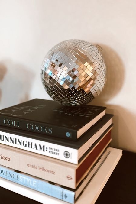 A bright spot in our entry way - layered books on style and food topped with a disco ball 🪩 

#LTKhome #LTKstyletip