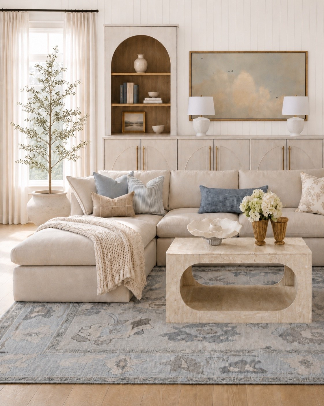 An all-season living room with just a subtle touch of coastal charm. 🤍

I wanted this design to feel calm, bright, and timeless — the kind of room that works just as well in January as it does in July. Soft neutrals, warm wood tones, layered texture, and muted blue accents give it that relaxed coastal feel without making the whole space feel overly beachy.

The oversized sectional keeps it cozy, the patterned blue rug adds softness, and the arched cabinet + vertical shiplap bring in that custom designer detail. I also love how the knit throw, woven vases, and sculptural travertine finish coffee table create textural interest to make the room feel collected and inviting.

Shop the look here for an elevated, livable living room with coastal charm you can enjoy year-round.

#LivingRoomDesign #CoastalDecor #DesignerLooksForLess

#LTKHome