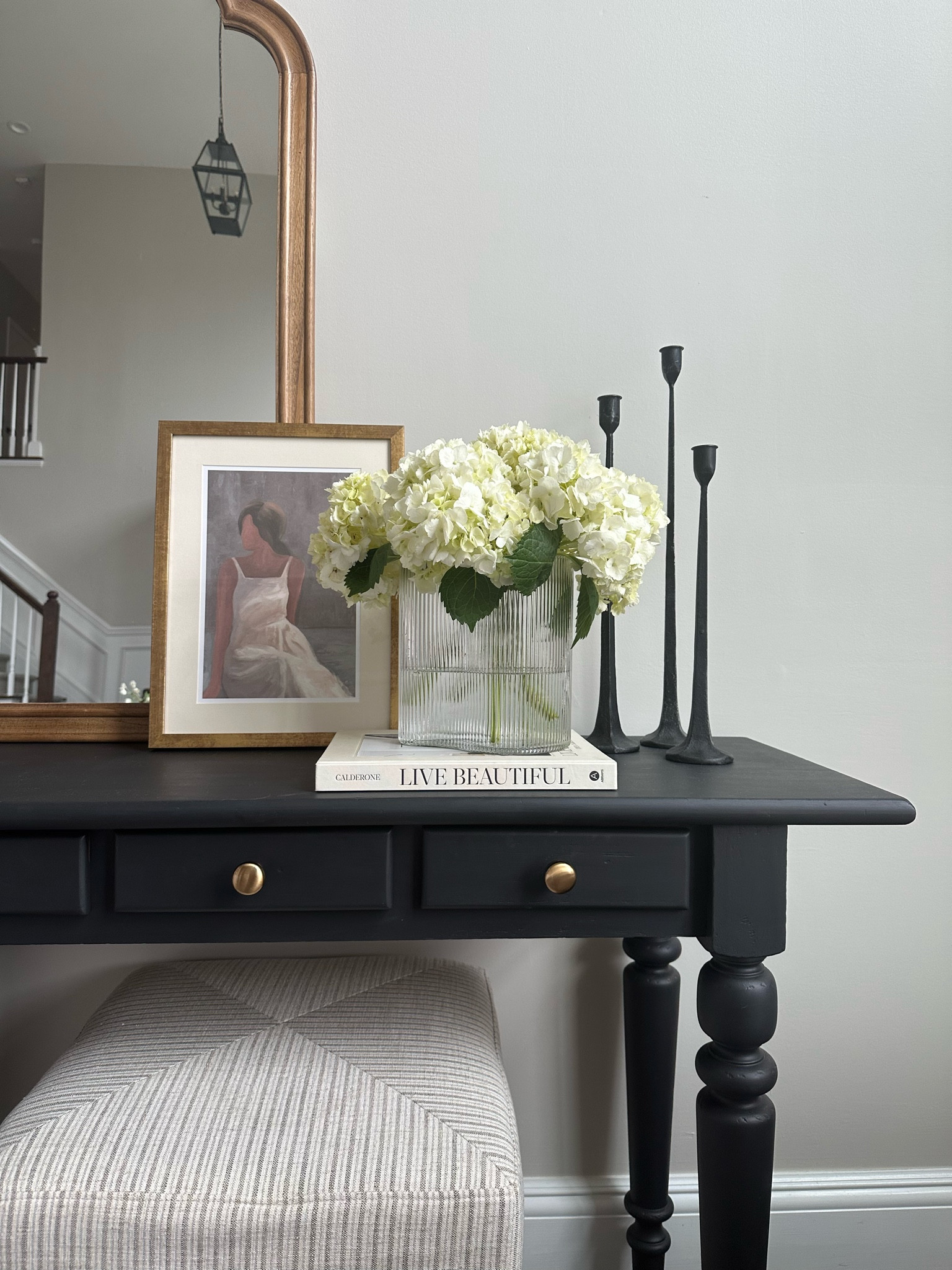 Console Styling
Beautiful ridged glass asymmetrical vase, candlesticks, art, coffee table book and ottoman.


#LTKhome