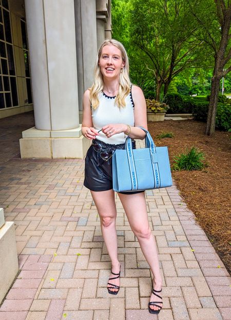 Summer work wear outfit. White high neck tank top with black trim, black leather shorts, black strappy sandals, blue Coach tote bag, cat eye sunglasses.

#LTKworkwear #LTKitbag #LTKstyletip