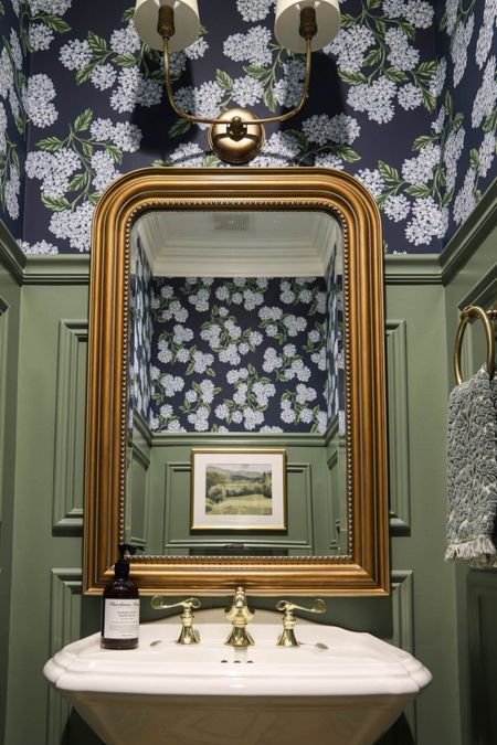 The brass Louis mirror is one of my favorite pieces of this powder room makeover! The hallway half-bathroom also includes navy hydrangea wallpaper, brass sconce, brass towel ring, pedestal sink and picture frame wall trim!

#LTKhome