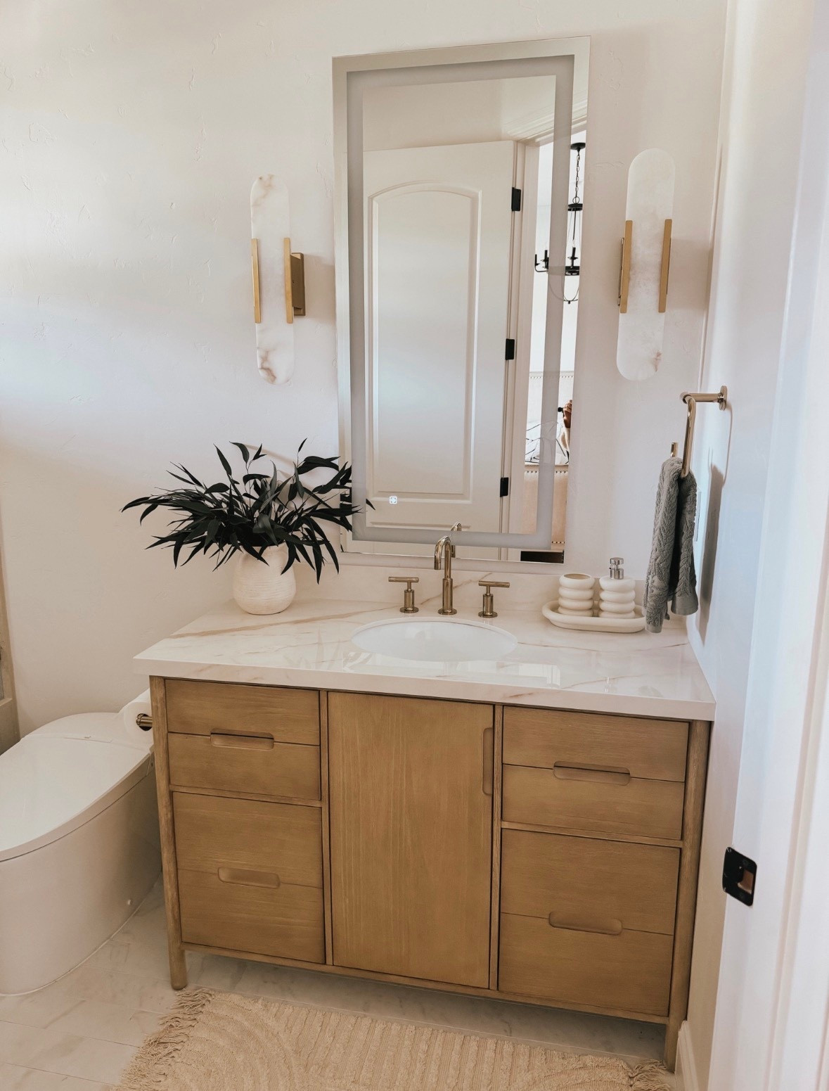 Love this bathroom vanity that comes with the marble top. The melange sconces are a show stopper plus the gold faucet and fixtures in this bathroom remodel 

