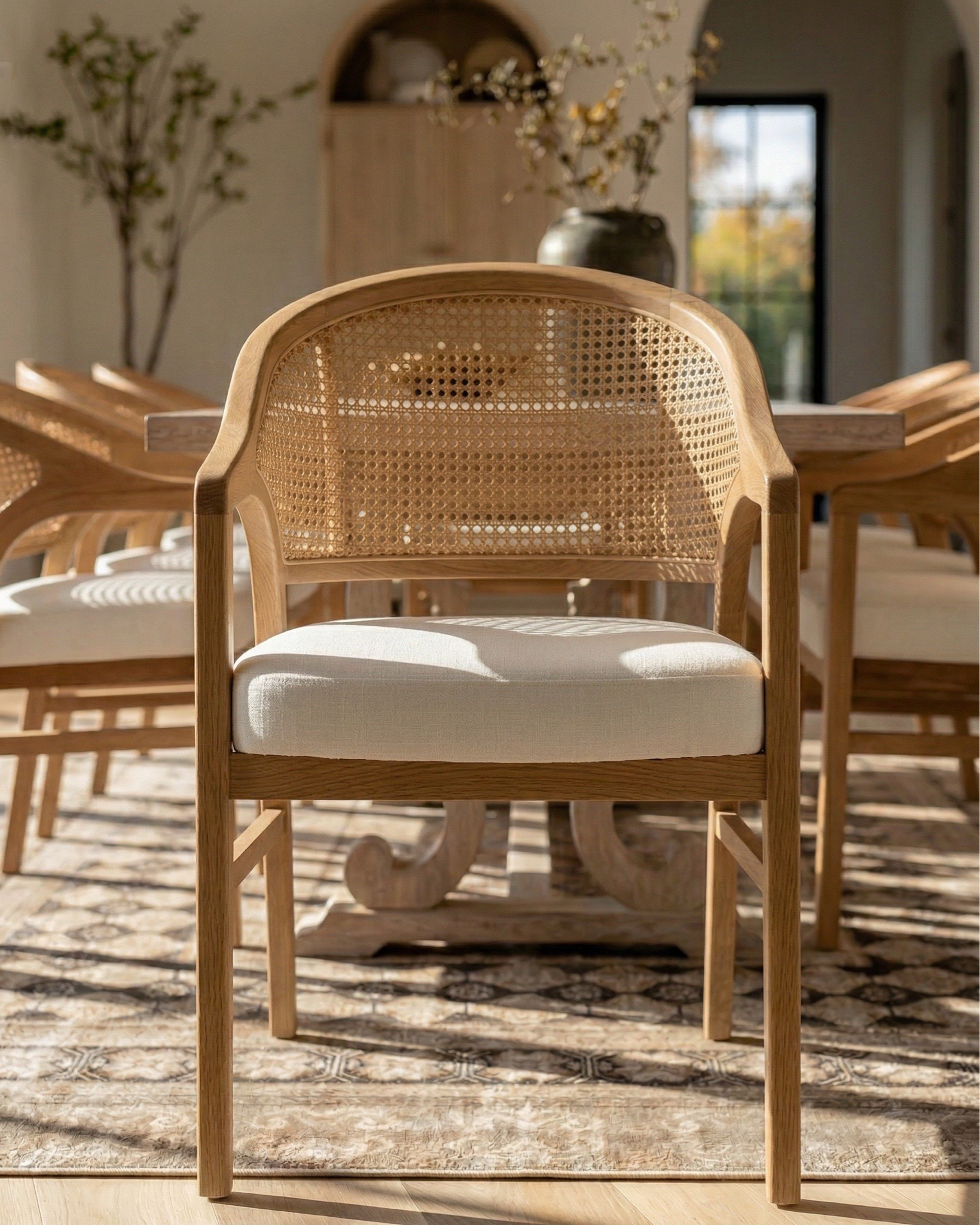 * Rectangular light wood dining table (traditional trestle base)
* Woven cane dining chairs (natural oak frame)
* Neutral vintage-style area rug (distressed pattern)
* Brass modern chandelier (linear / sculptural arms)
* Rustic exposed wood ceiling beams (reclaimed look)
* Large black-framed sliding glass doors (industrial style)
* Dark ceramic vase (handmade / organic texture)
* Dried floral arrangement (neutral stems)
* Sculptural brass decorative bowl
* Black ceramic candle holder (modern abstract form)
* White taper candle
* Small matte black decorative bowl
* Minimalist sculptural object (black accent piece)
* Light wood sideboard cabinet (fluted / ribbed detailing)
* Built-in arched niche cabinet (custom millwork look)
* Decorative pottery (neutral ceramic vases)
* Framed landscape wall art (classic / muted tones)
* Indoor olive tree (or faux olive tree)
* Neutral linen / textured textiles
* Warm light oak flooring
* Soft cream / off-white wall paint
* Arched doorway architectural detail


#LTKHome #LTKSaleAlert