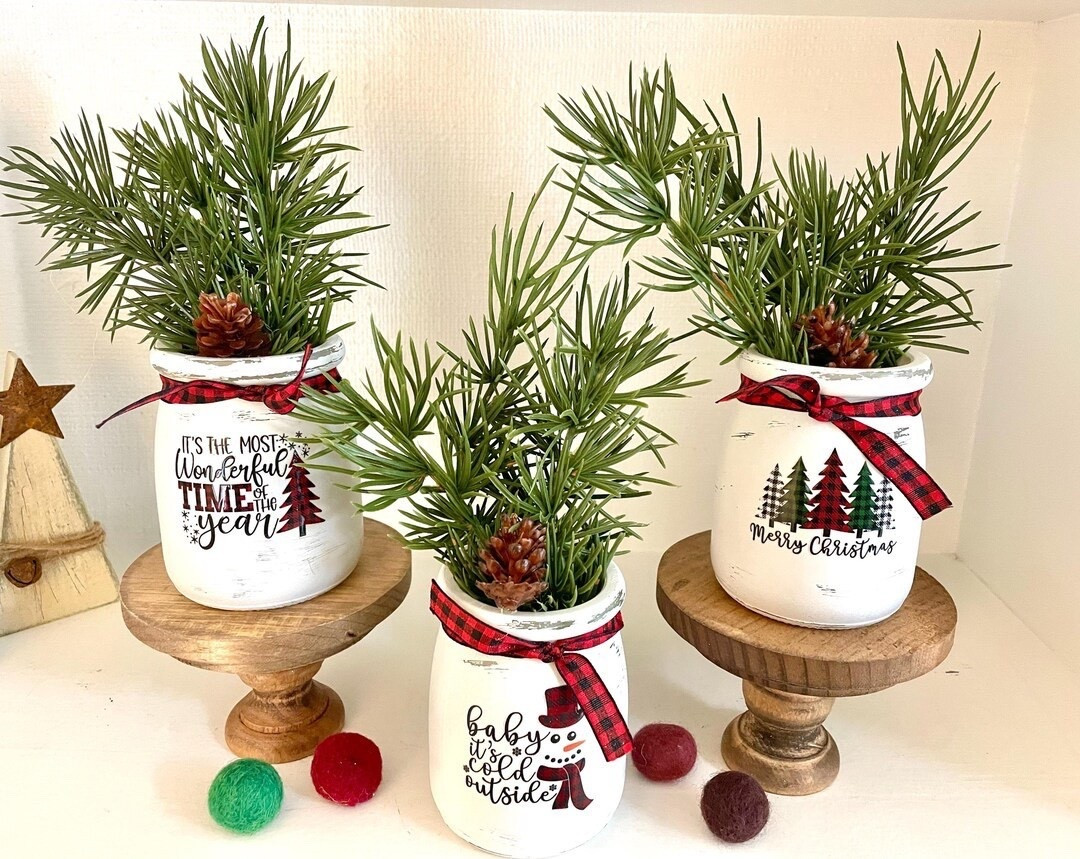 Add cozy farmhouse charm to your holiday decor with these Christmas vases with pine branches 🎄 Each vase comes adorned with buffalo plaid ribbon and a lightly distressed finish for that rustic, festive feel. Perfectly sized for tiered trays, shelves, or mantels, they bring a warm seasonal touch to any space. Pair them with the matching wooden pedestal risers to add height and dimension to your display. A wonderful hostess or teacher gift that spreads holiday cheer in style! ❤️✨

#FarmhouseChristmas #TieredTrayDecor #RusticHoliday #EtsyFinds #ChristmasVases #BuffaloPlaid #HolidayHome #GiftIdeas #HostessGift #TeacherGift

#LTKHome #LTKFindsUnder50 #LTKSeasonal