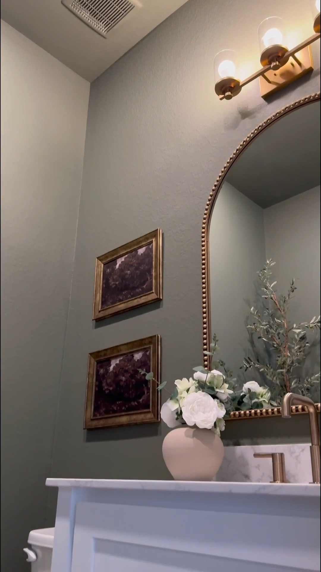 If you’re considering painting your powder room green, I’m telling you, THIS might be the perfect color for you … go for it! 

I used flat finish for the walls and painted the baseboards in satin finish… 

I’ll be honest, I was apprehensive at first … I even paintings the ceiling 😬 believe it our not, it made the room feel larger! 

I chose brass finishes bc I really wanted the space to have a vintage feel… well, modern vintage…??? If that’s a thing 😆.. 

The mirror is 30x40 inches… 

I added a new light fixture and it now faces upwards … which made that wall feel taller 

I wasn’t in love with this builder grade vanity tbh😆, matter-fact, I wanted to change it… it wasn’t functional …but now i wanna keep it lol 😂… I added brass hardware, these cute baskets from Walmart, led light strips on the bottom and now it’s a whole new unit….. you can even add battery powered/rechargeable/plug in led light strips .. whatever fits your lifestyle 

Ok let’s talk about this stunning planter!!! …. You know I love me an olive tree 😆… and I wanted something tell and slim… this planter was the perfect for plus it added to the moodiness 🥰

I am in love with this space… I wanted to create a vintage-cottagy feel in this powder room, while the rest of the home feels modern. #LTKVideo

#LTKHome #LTKStyleTip