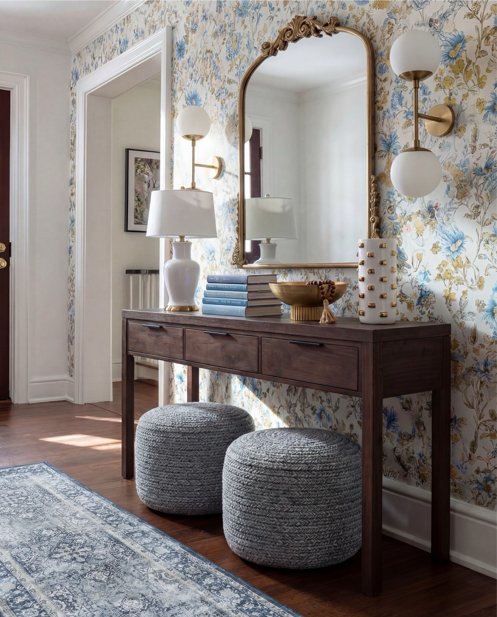 Shop the Look:
• Dark wood console table
• Blue + gold floral wallpaper
• Chunky woven poufs (cool grey)
• Brass globe sconces
• White ceramic table lamp
• Gold decorative bowl
• White studded ceramic vase
• Blue vintage-style runner
• Coffee table books (blue spines for color continuity)

#LTKHome #LTKSaleAlert
