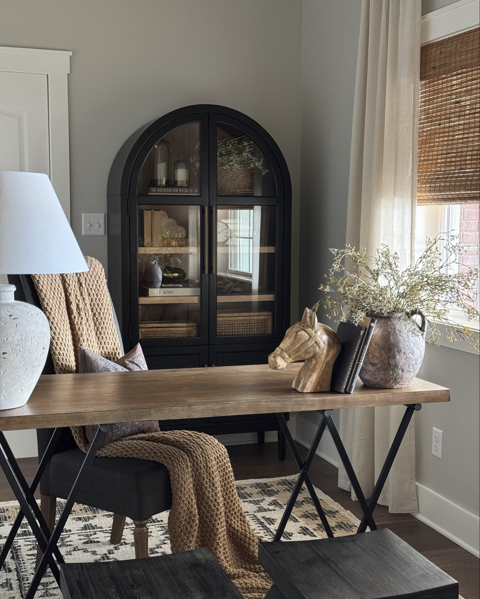 Who says storage can’t be beautiful?
This arched black cabinet is one of my favorite pieces in our home office—it’s functional and pretty, with its rattan texture, warm wood shelves, and classic, timeless silhouette. It’s the kind of piece that works just about anywhere—entryway, dining room, office, or bedroom.

I kept the styling simple and timeless with:
– Decor books stacked to add height
– Neutral vases + faux greenery for some texture
– A mix of woven baskets, brass accents, and a favorite sculptural piece for interest
– And of course… a cute clock because I’m always losing track of time when I decorate.

You can find everything linked here—including the cabinet and all the decor I styled inside.
Follow me on LTK to shop it all and get more styling ideas straight to your feed!

#LTKHome