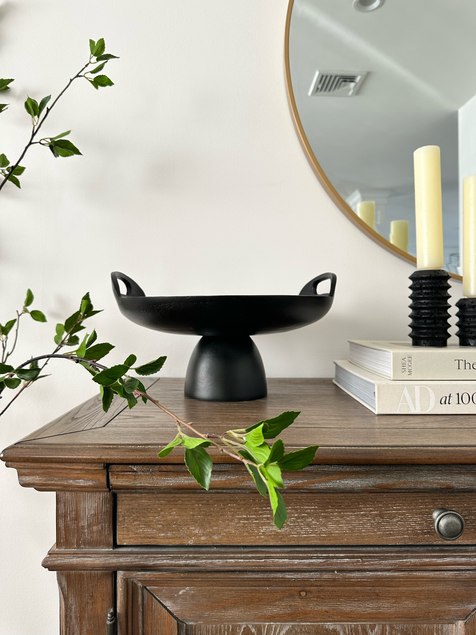 Modern console table decor. Black pedestal bowl, travertine candle holders, gold round mirror  

#LTKHome