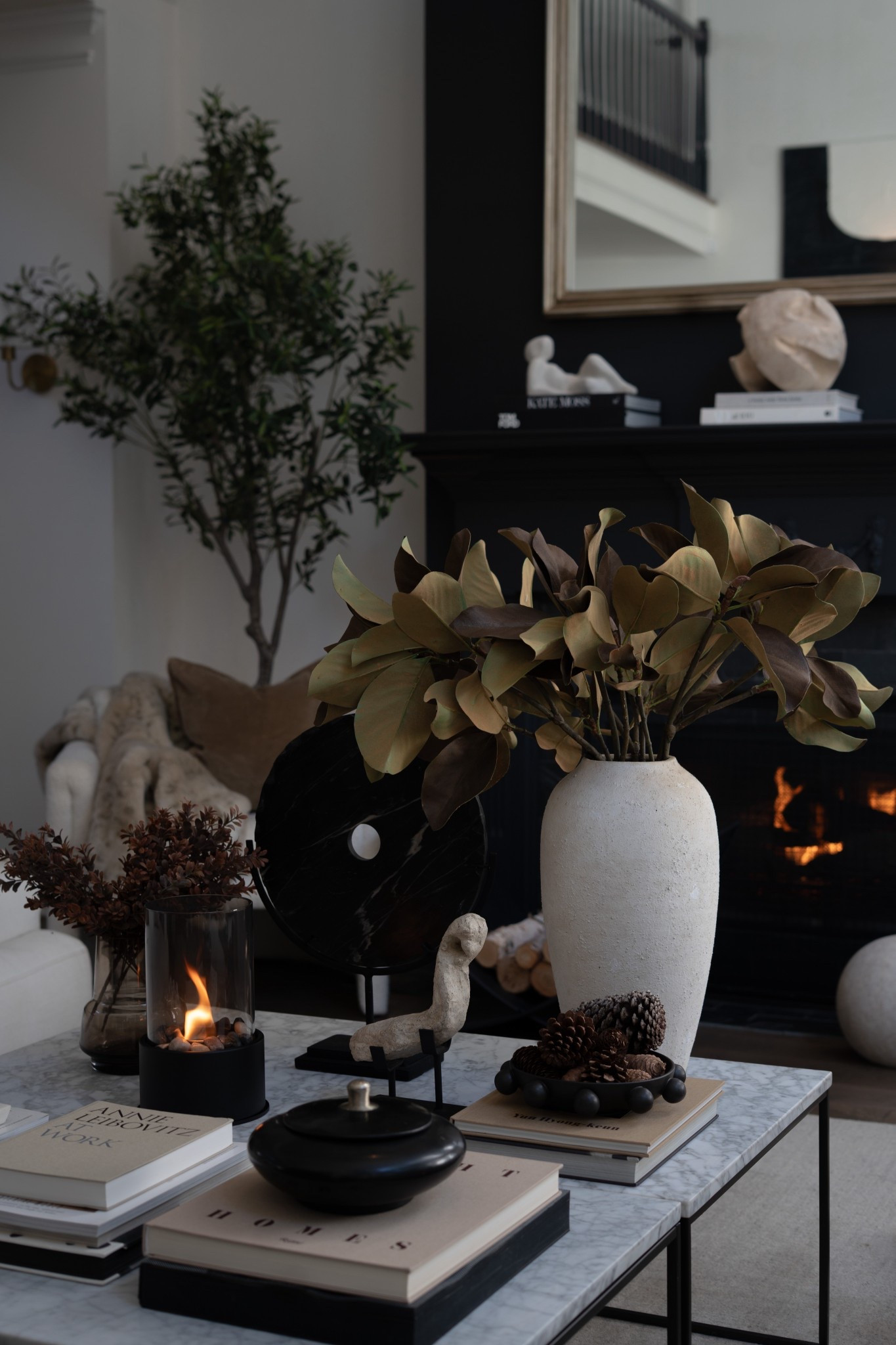 This cozy corner of the living room is giving me *all* the fall feels! 🍂 I am absolutely smitten with how these faux magnolia stems transform the space — the warm, leathery leaves instantly bring in that autumn richness without being too “pumpkin patch cliché.” Paired with soft textures, moody blacks, and the glow of the fire, the magnolia branches add just the right balance of natural warmth and modern elegance. Honestly, they’re the kind of piece that makes the room feel polished yet inviting, the perfect way to transition your home into fall without overwhelming it.


#LTKHome #LTKStyleTip #LTKSeasonal