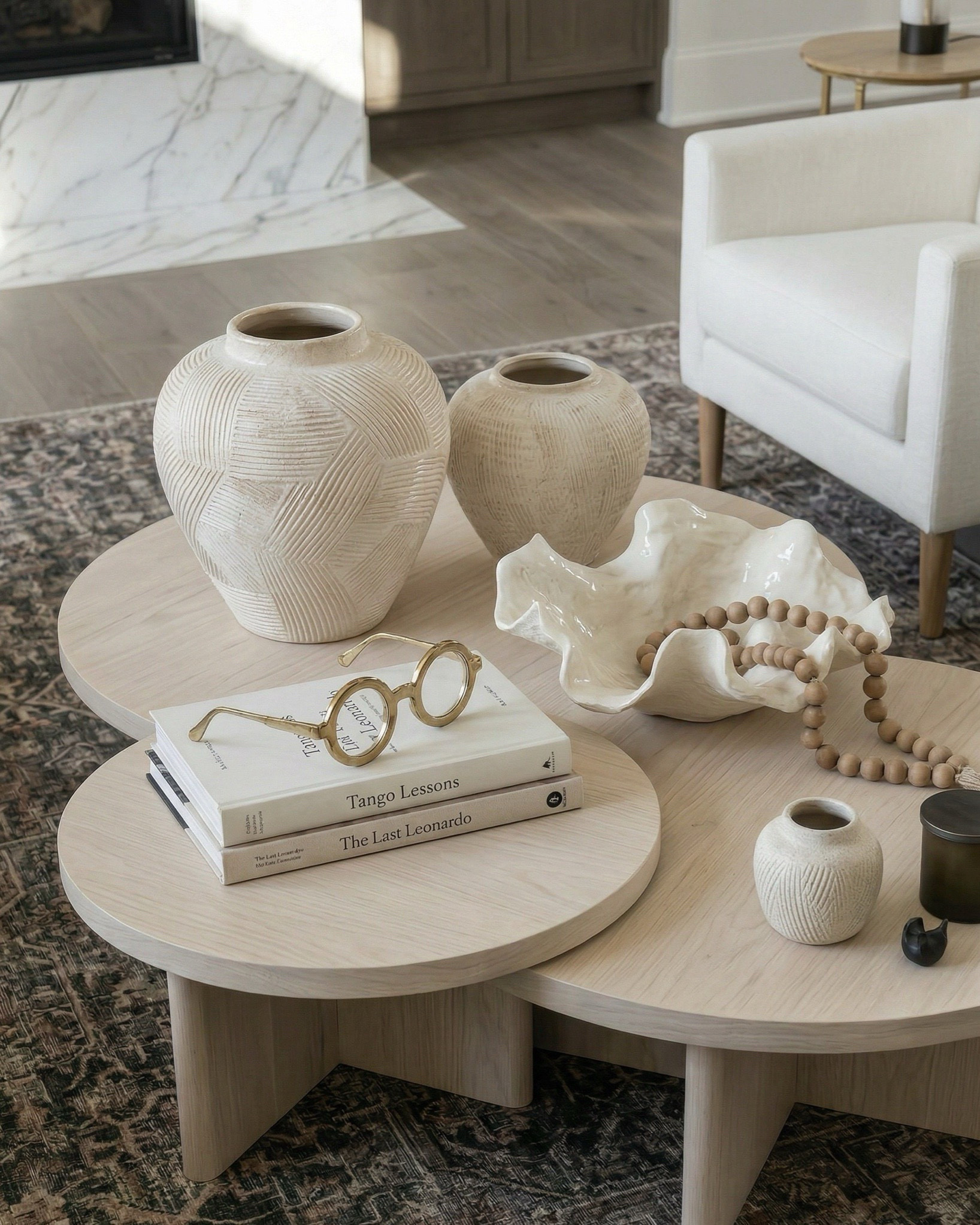 Shop the look:
• Cream upholstered sofa / neutral fabric couch • Ivory boucle accent chairs • Round light wood coffee table • Textured boucle ottomans / foot stools • Vintage distressed area rug (neutral patterned rug) • Marble slab fireplace wall / stone fireplace design • Custom built-in shelving / wood built-ins • Decorative vases (ceramic + sculptural decor) • Coffee table books + tray styling decor • Wood console table (rustic entryway table) • Upholstered bench / small stool • Brass table lamp with patterned shade • Glass + brass side table • Framed abstract wall art (neutral artwork) • Wall sconces with globe lighting • Olive branch stems / faux greenery • Woven throw blanket / textured throw • Decorative beads / bowl accents

#LTKhome #LTKsale #LTKstyletip