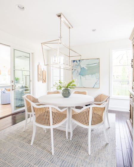 Our old dining room decorated in neutral colors. Items include a blue and white modern rug, round white dining table, cane dining chairs, blue and green abstract art, a linear chandelier and faux greenery. 

spring dining room, blue and white decor #ltkhome #ltkseasonal #ltksalealert #ltkfindsunder50 #ltkstyletip #ltkfindsunder100  Easter dining room, spring dining roomm

#LTKSeasonal #LTKsalealert #LTKhome