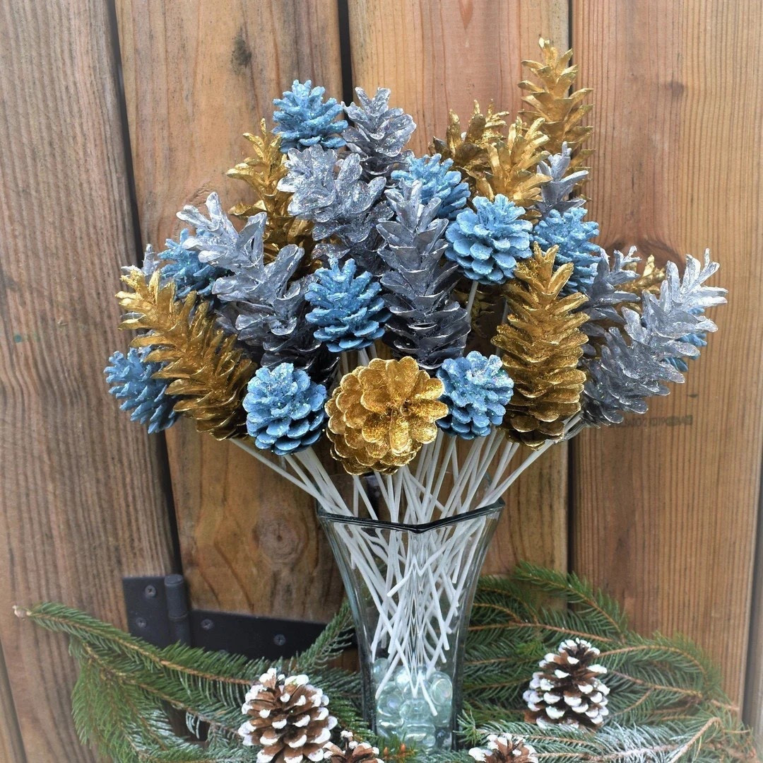 Add sparkle and winter charm to your home with this handcrafted set of glittered pinecone flowers. Each dozen features silver, gold, and French blue pinecones carefully painted and sprinkled with holographic glitter, mounted on hand-painted 9” white stems for a long-lasting, elegant display. Perfect for vases or incorporated into larger arrangements, these unique pinecone flowers make stunning centerpieces for New Year celebrations or any winter gathering. Ethically collected and baked pinecones from Michigan add a touch of nature and adventure to every piece.

#LTKhome #LTKseasonal #WinterDecor #PineconeDecor #HandmadeHome #EtsyFinds #HolidayCenterpiece #RusticWinter #FestiveDecor

#LTKHoliday #LTKSeasonal #LTKHome