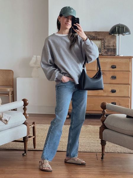 Caroline Joy of Unfancy wears a casual spring outfit featuring mid rise Abercrombie jeans, a Reformation grey sweatshirt, Birkenstock Arizona sandals, and the Polene Umi bag. 