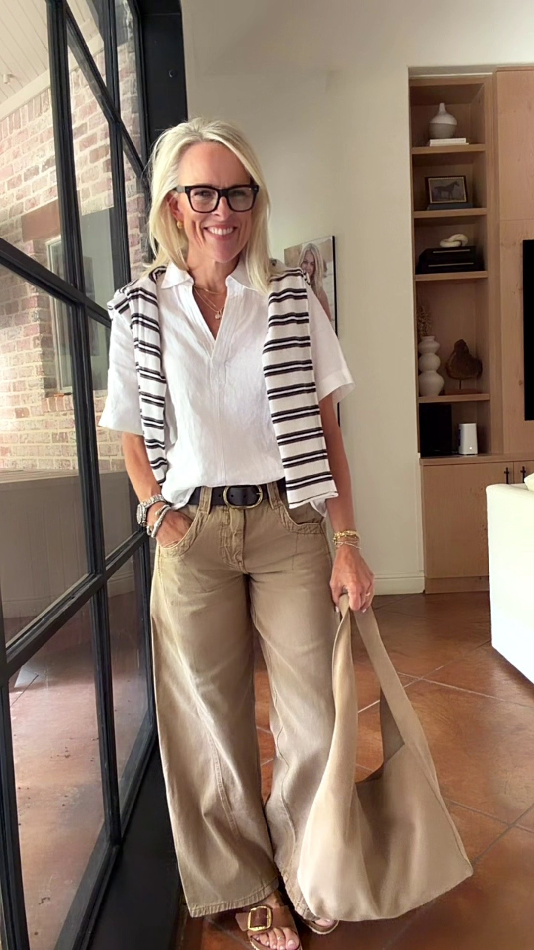 A white button-down, striped sweater draped over the shoulders, and relaxed wide-leg khaki jeans make such an easy, polished casual outfit. I love how these classic pieces work together for everyday wear, whether you're heading to lunch, running errands, or enjoying a weekend out.
I’ve linked a few shoe alternatives, too, since the sandals pictured may be low in stock or sold out. Loafers and sneakers would both work beautifully with this look!