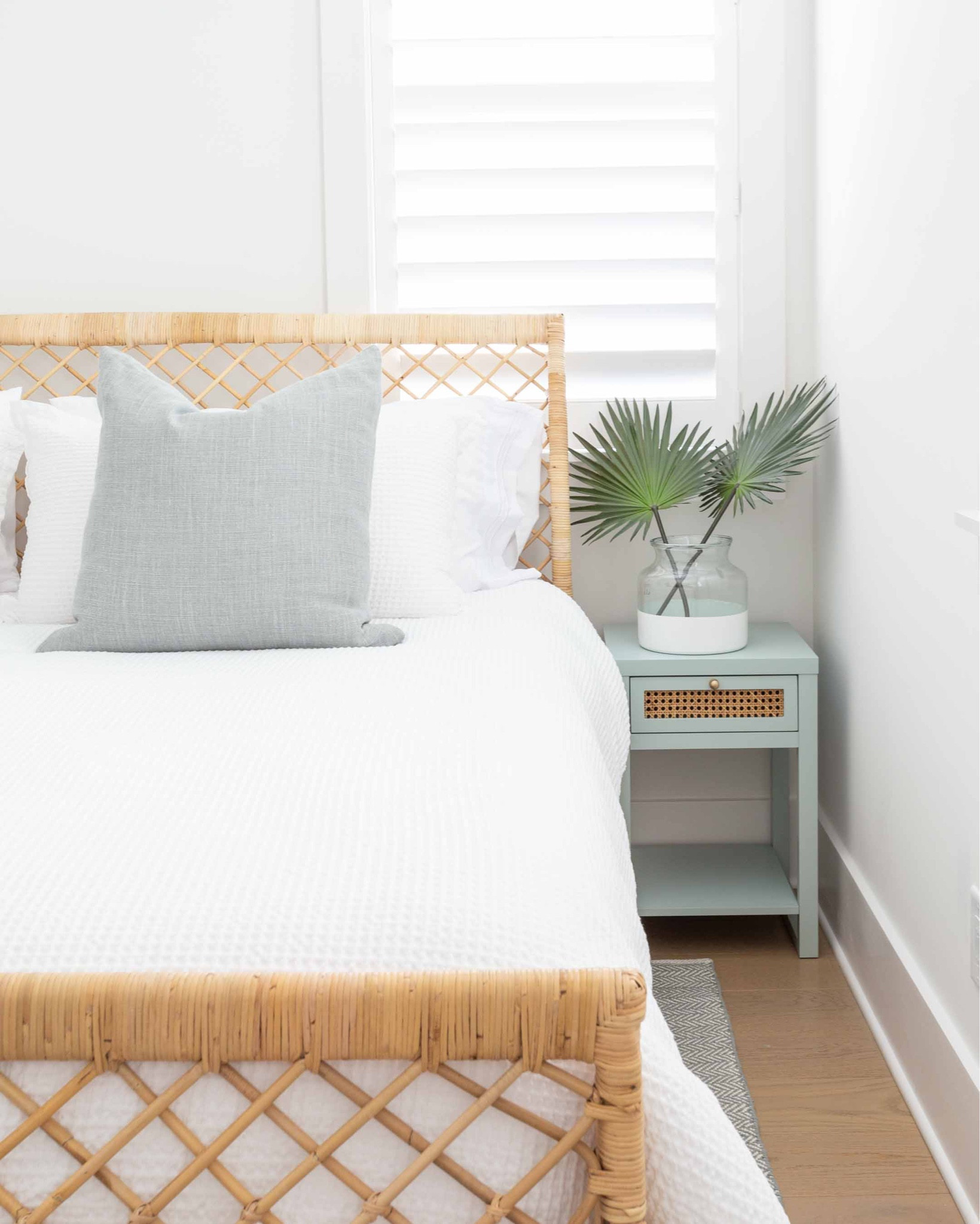 Our Florida carriage house bedroom featuring a rattan bed frame, Swedish blue herringbone rug, white waffle knit bedding, light blue and cane nightstands,  and faux palm leaves. Take the full tour here: https://lifeonvirginiastreet.com/our-florida-carriage-house-tour/
.
#ltkhome #ltkseasonal #ltkfindsunder50 #ltkfindunder100 #ltkstyletip #ltkover40 #ltktravel coastal bedroom decor, Serena & Lily style, neutral bedroom decor

#LTKSeasonal #LTKhome #LTKsalealert