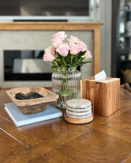 Coffee table styling can be tricky with a square table, but I always try to go for function that is also pretty. Something people comment about all the time when they visit is that they love the tissue box here. I think it’s vital to have tissues available all over the house, so I just put them in covers to make them look pretty. 
These marble coasters are the perfect touch to tie it all together. And the remotes can all be easily wrangled in a carved bowl. I break up all the wood with a coffee table book and a glass or ceramic vase with greenery or flowers. 



#LTKhome #LTKfindsunder50 #LTKsalealert