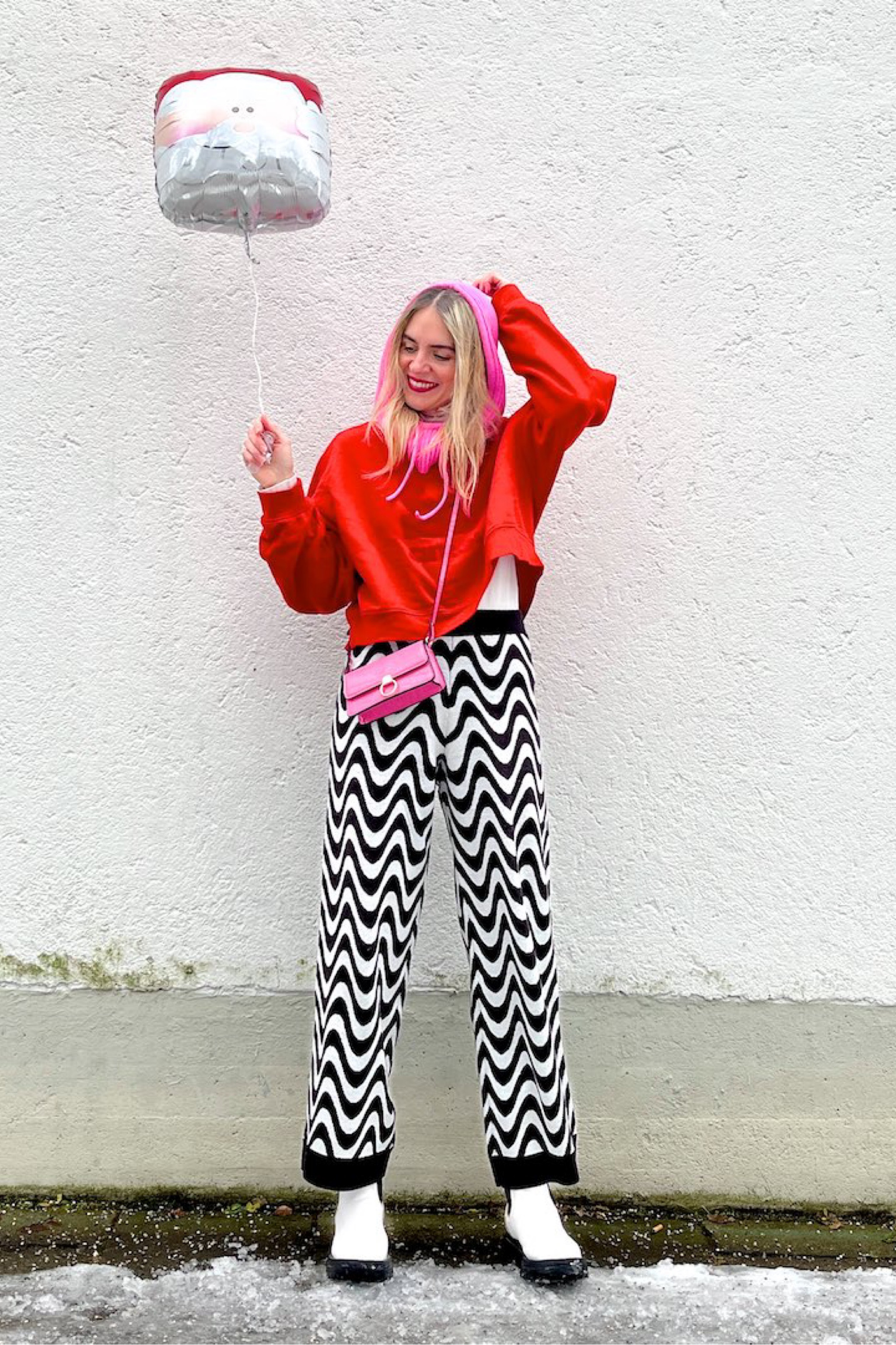Merry Christmas 2022. Fashion Blogger Girl by Style Blog Heartfelt Hunt. Girl with blond hair wearing a pink balaclava, red sweatshirt, funky knit pants, pink mini bag and white chunky boots. #colorfuloutfit #colorfulstyle #colorfulfashion #colorfullooks #fashionfun #cutefalloutfit #fallfashion2022 #falllookbook #fitcheck #dailylooks #dailylookbook #contentcreator #microinfluencer #discoverunder20k 