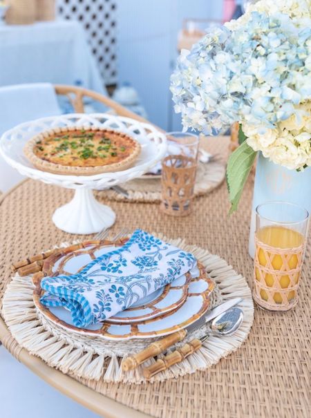 Outdoor place setting with bamboo melamine plates, raffia chargers, blue floral scalloped edge napkins, wrapped cane glassware, a dipped ceramic vase, and bamboo flatware

#potterybarn #outdoorentertaining #tabletop #markandgraham #lindroth 

#LTKFind #LTKhome #LTKSeasonal
